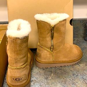 gold zipper on the side which zips up and down. Fur inside. Ugg logo on the back
